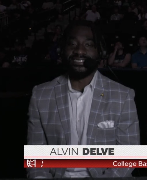 Alvin Delve in a gray suit on the broadcast desk